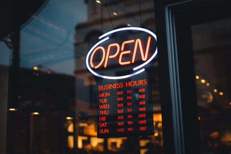 Bordje met openingstijden achter een etalageraam
