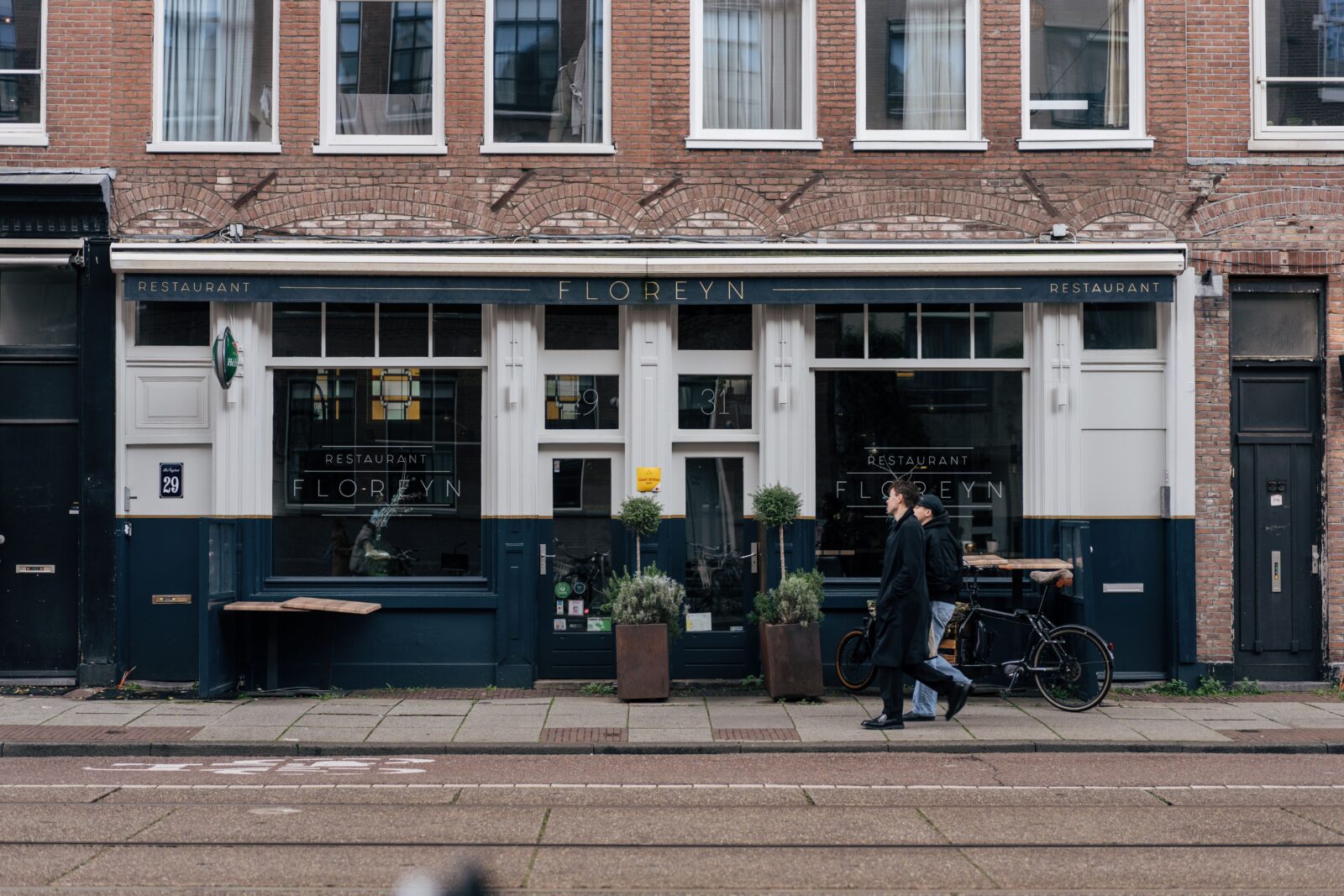 Voetgangers lopen langs een restaurant in een Amsterdamse straat