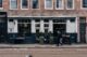 Voetgangers lopen langs een restaurant in een Amsterdamse straat