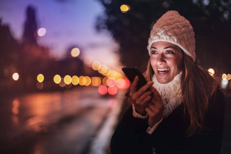Vrouw spreekt een bericht in op haar smartphone op straat
