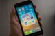 Une main tient un smartphone avec des applications de réseaux sociaux à l'écran