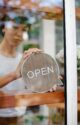 Un propriétaire de café montre le panneau "ouvert" devant son établissement