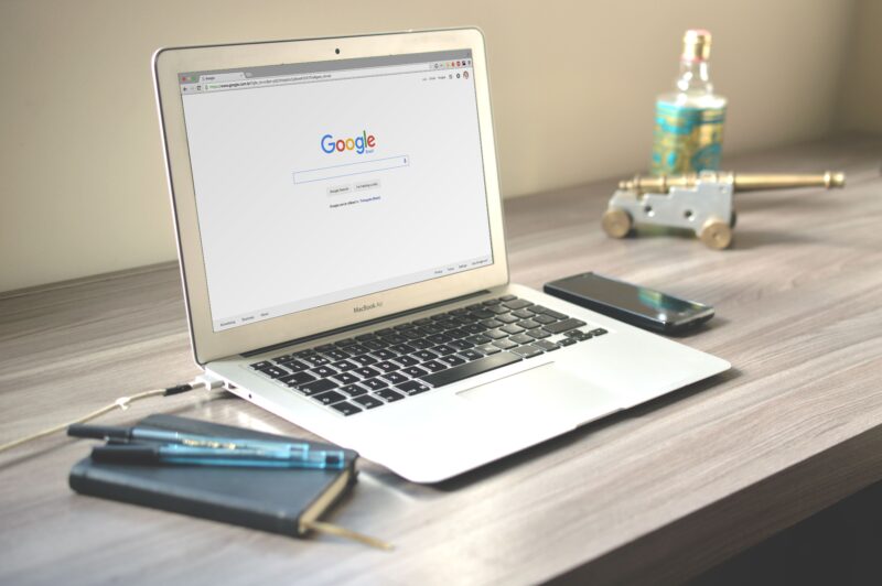 Laptop met een Google-zoekpagina op een opgeruimd houten bureau