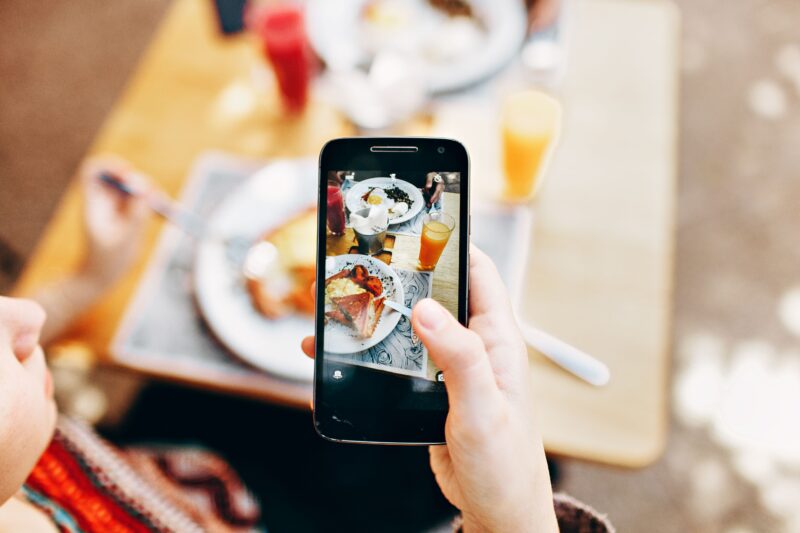 Persoon maakt met een smartphone een foto van geserveerd eten