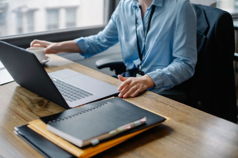 Eine Frau arbeitet an einem Laptop mit einer Tasse Kaffee